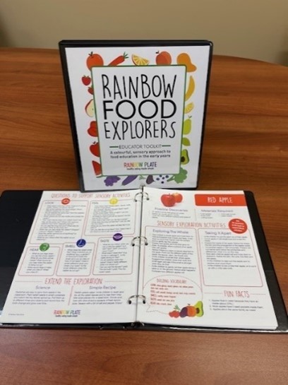 Rainbow Food Explorers toolkit binder, open to sample pages of the resource